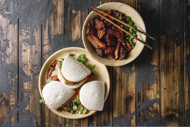 Bao buns and chinese food on plates and in bowls used as a pantry lifestyle image